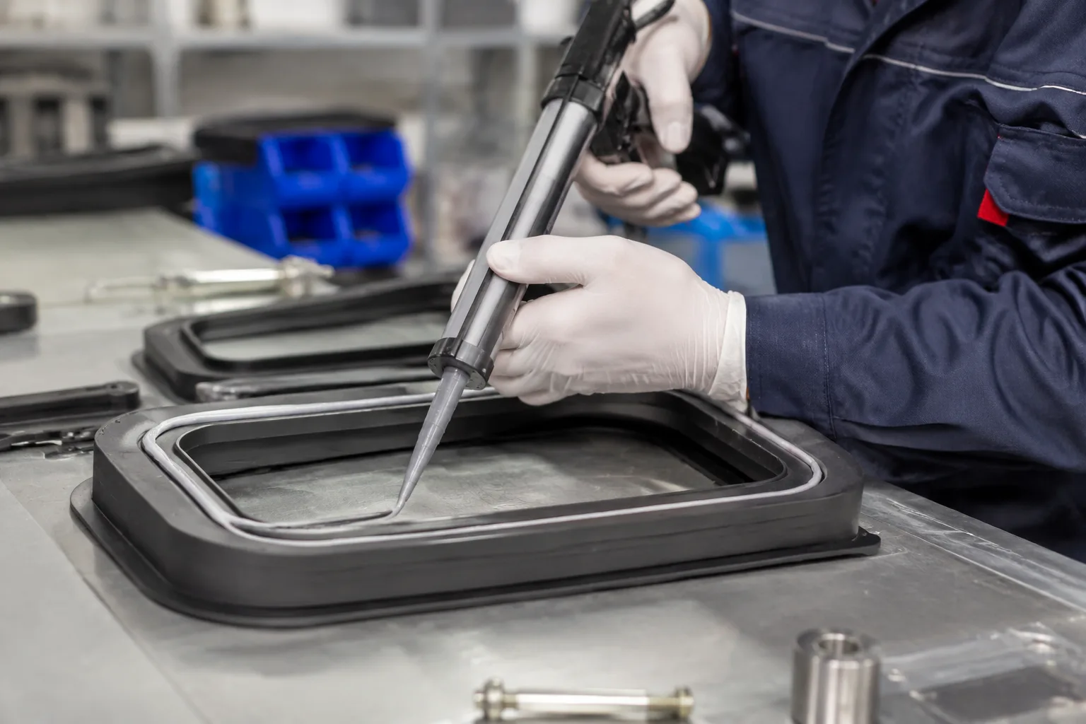 Un espacio de trabajo técnico donde se utiliza adhesivo impermeable para unir piezas de caucho a metal, haciendo hincapié en el procedimiento correcto y el enfoque industrial.