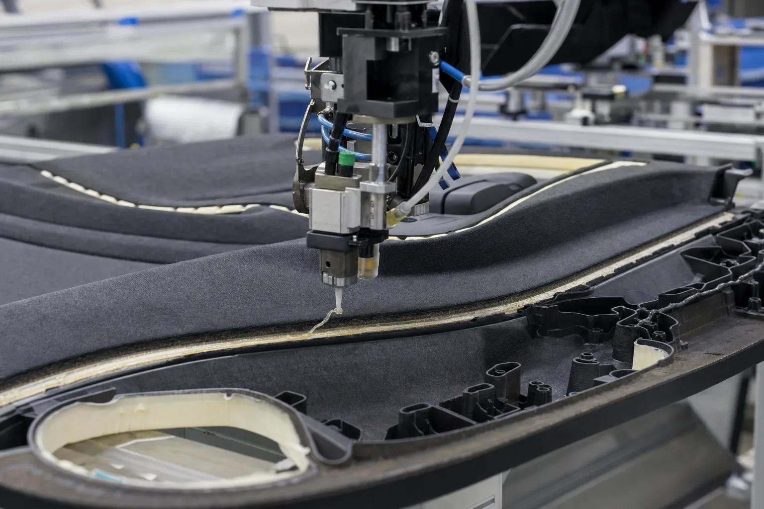 This image visualizes robotic adhesive application onto a door trim part, demonstrating the process of joining fabric and plastic layers in auto interior manufacturing.